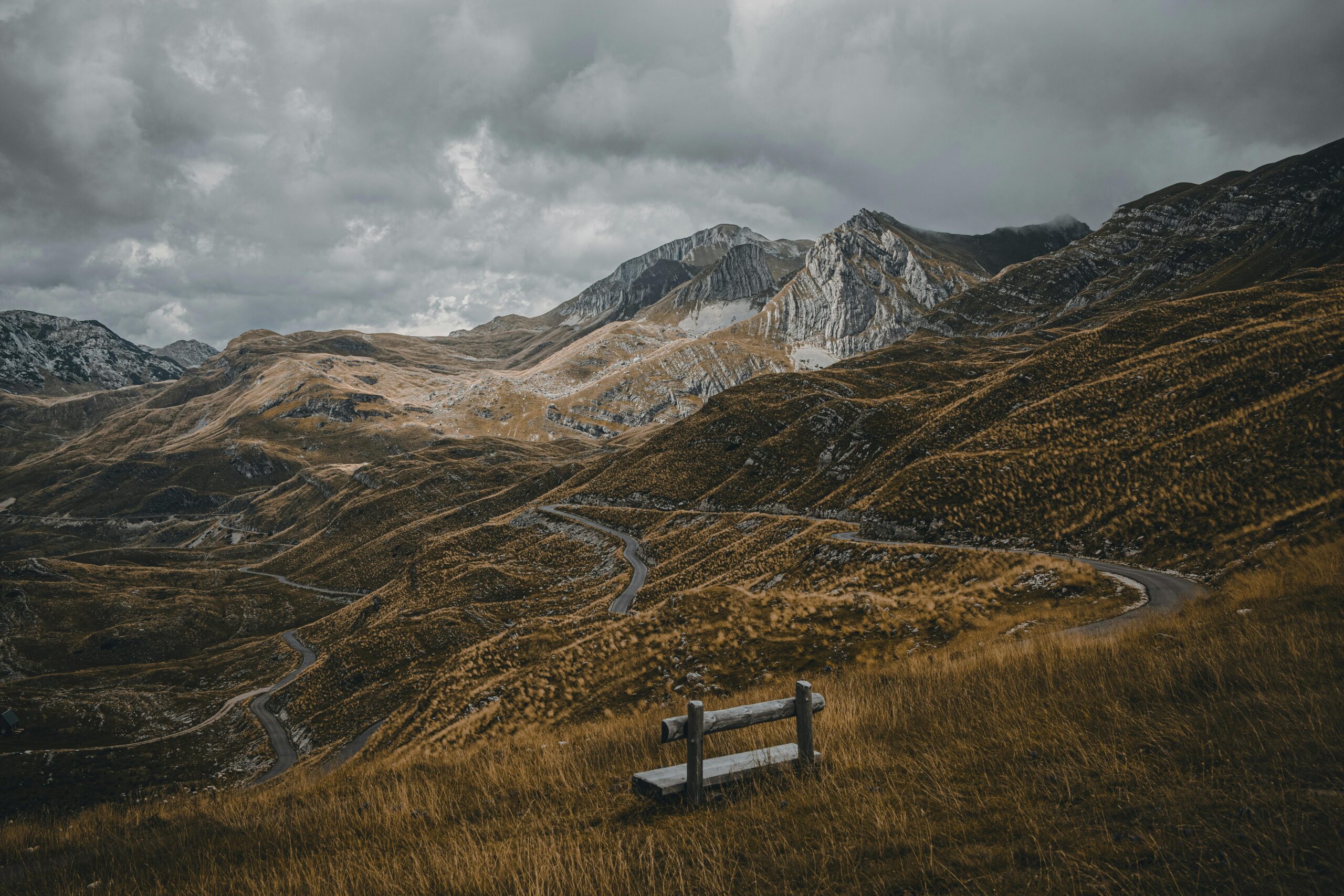 Dramatic mountain landscape in Žabljak, Montenegro with winding road and bench.