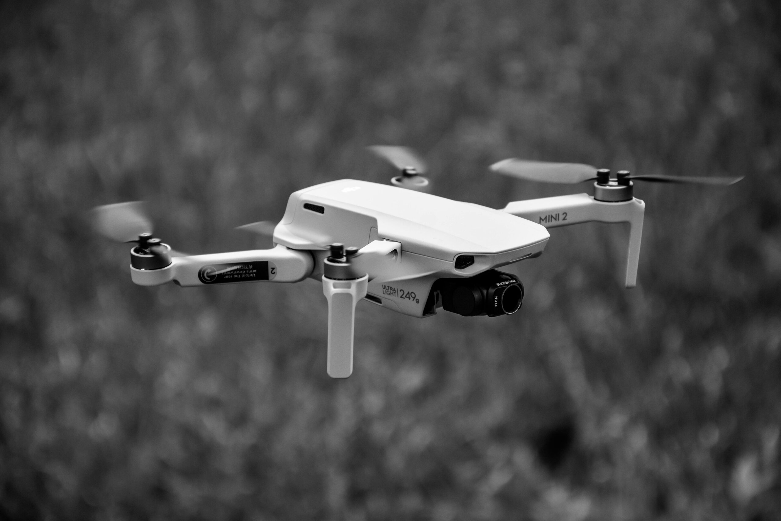 A grayscale image of a hovering drone outdoors, showcasing its sleek design and motion.